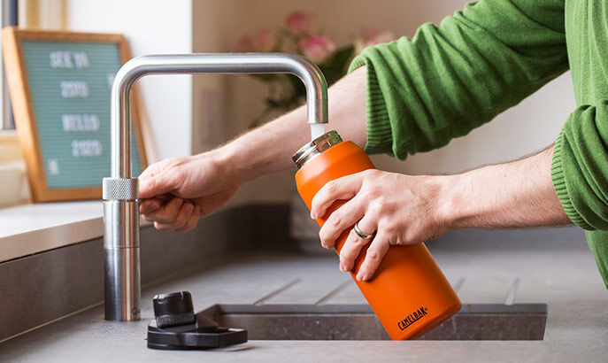 Orange bottle being cleaned in sink